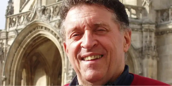Homme souriant devant une cathédrale gothique